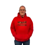 Man wearing a red Howzit Canada hoodie, smiling and standing with hands in pockets.