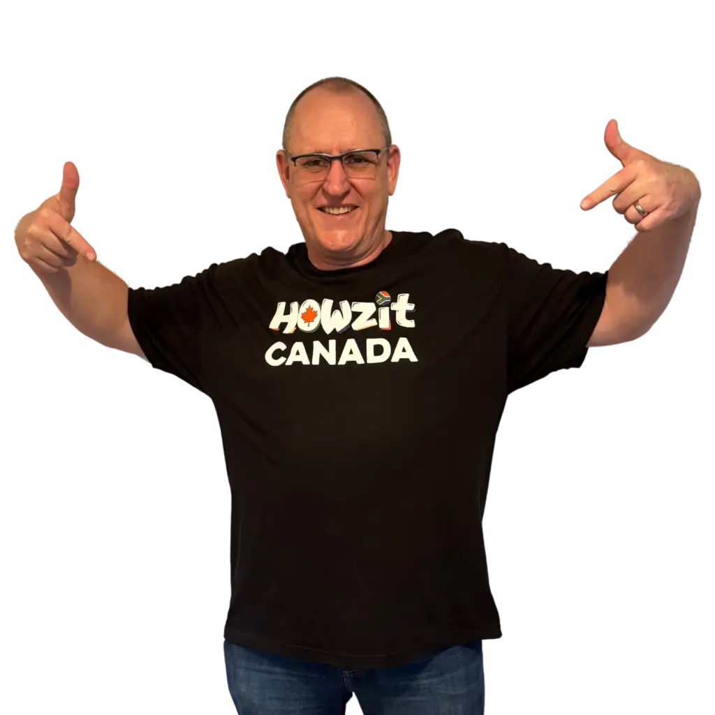 Man wearing a black Howzit Canada T-shirt, pointing to the logo on the front with a big smile.