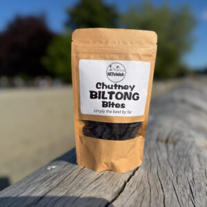 Chutney biltong bites snack pack photographed on a beach log in West Vancouver