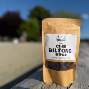 Chilli biltong bites snack pack on a driftwood log at Ambleside Beach in West Vancouver