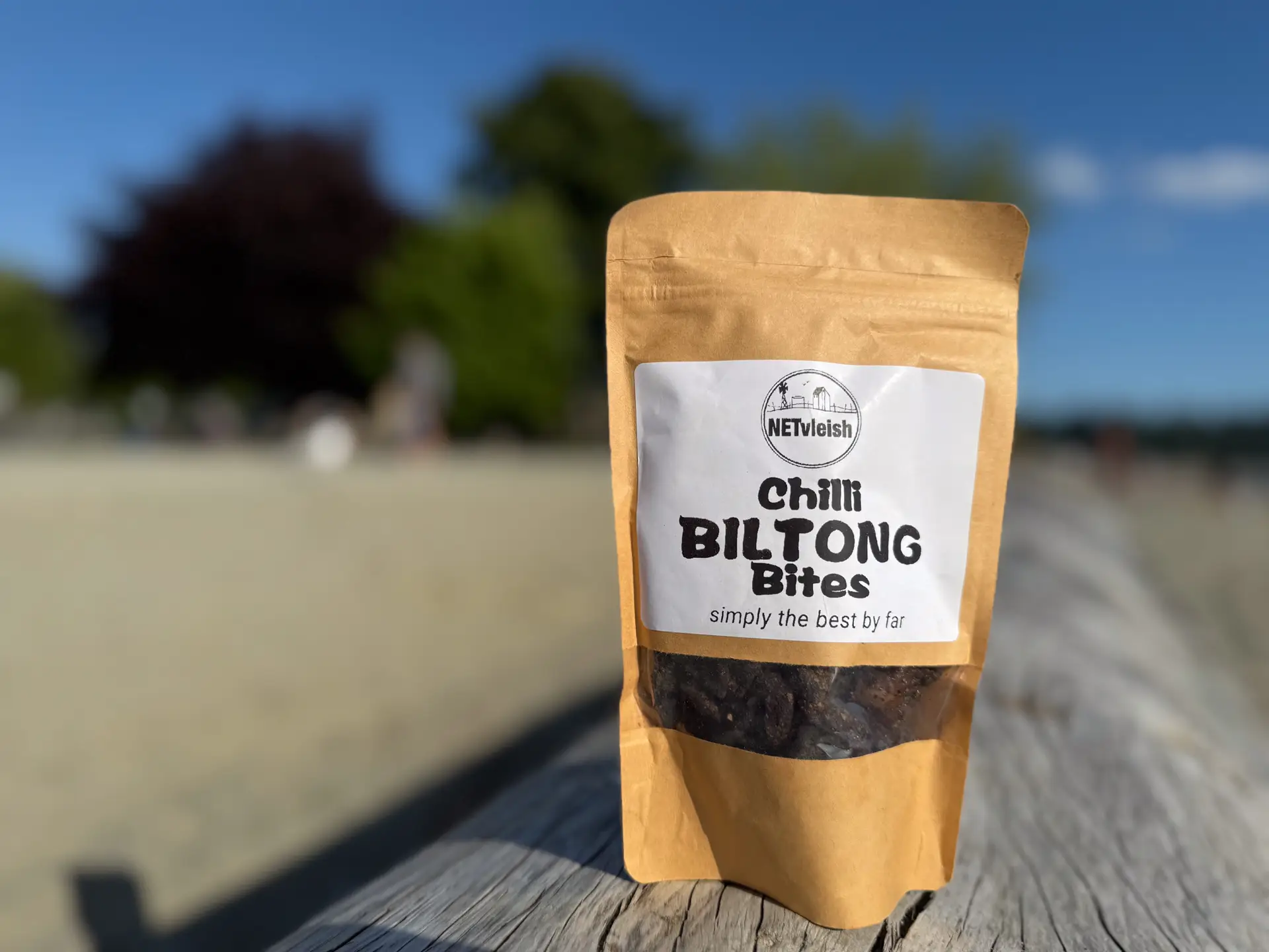Chilli biltong bites snack pack on a driftwood log at Ambleside Beach in West Vancouver