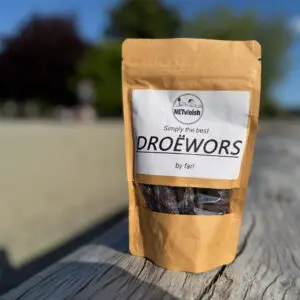 Packet of South African droëwors placed on a driftwood log at Ambleside Beach in West Vancouver