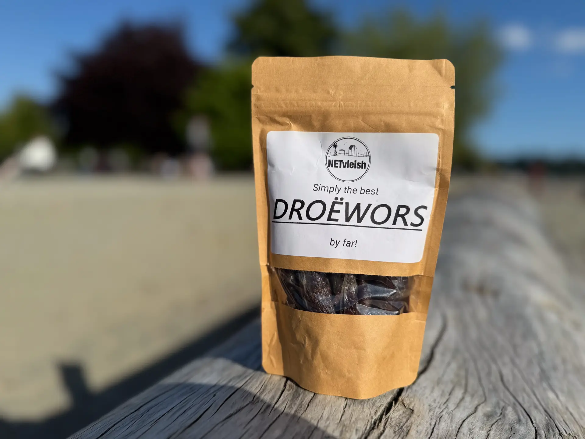 Packet of South African droëwors placed on a driftwood log at Ambleside Beach in West Vancouver